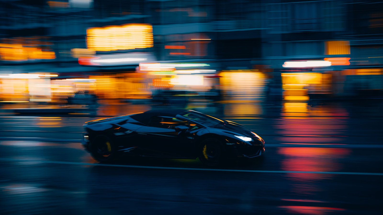 A black luxury sedan on a city street at night